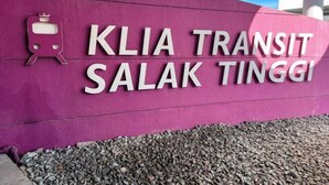 Eine violette Wand mit dem Schriftzug "KLIA TRANSIT SALAK TINGGI" und einem kleinen Zug-Symbol.