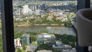 A cityscape view from a high-rise window, including buildings, a river, and a bridge.