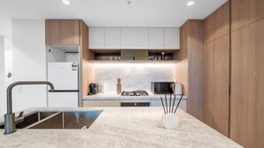 A modern kitchen with a marble countertop, built-in appliances, and wooden cabinets.