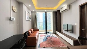 A modern living room with a sofa, a coffee table, a TV, and a large window with curtains. - Vinhomes Skylake Premier Residence Ha Noi - Marina Housing (Hanoi)