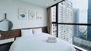A hotel room with a large bed, a bedside table, a mirror, and a window with a city view. - Vinhomes Skylake Premier Residence Ha Noi - Marina Housing (Hanoi)