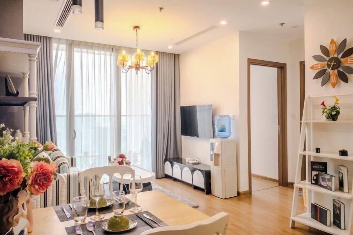 Uma sala de estar moderna com área de jantar, televisão, dispensador de água e estante de livros.