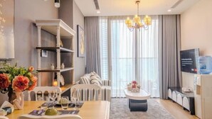 A modern living room with a dining area, a chandelier, a water dispenser, and a television. - Vinhomes Skylake Premier Residence Ha Noi - Marina Housing (Hanoi)