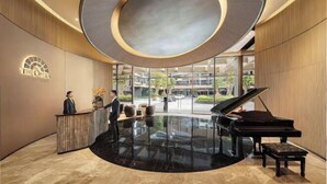 A lobby with a grand piano, a reception desk, and a circular ceiling design. - The Metropole Signature Collection – Galleria, Crest & Opera (Ho Chi Minh City)