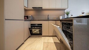 A modern kitchen with built-in appliances, a dishwasher, and a countertop with a sink. - The Metropole Signature Collection – Galleria, Crest & Opera (Ho Chi Minh City)