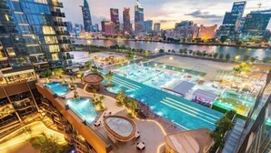 A high-rise hotel with a rooftop pool area, multiple swimming pools, and a city skyline view. - The Metropole Signature Collection – Galleria, Crest & Opera (Ho Chi Minh City)