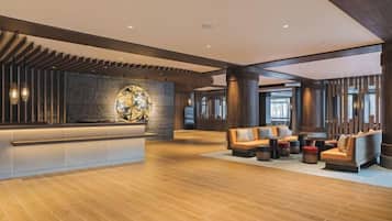 A spacious lobby with a reception desk, seating area, and large windows allowing natural light.