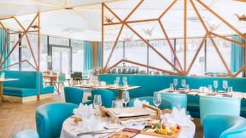 A restaurant with round tables, blue seating, and a geometric ceiling design.