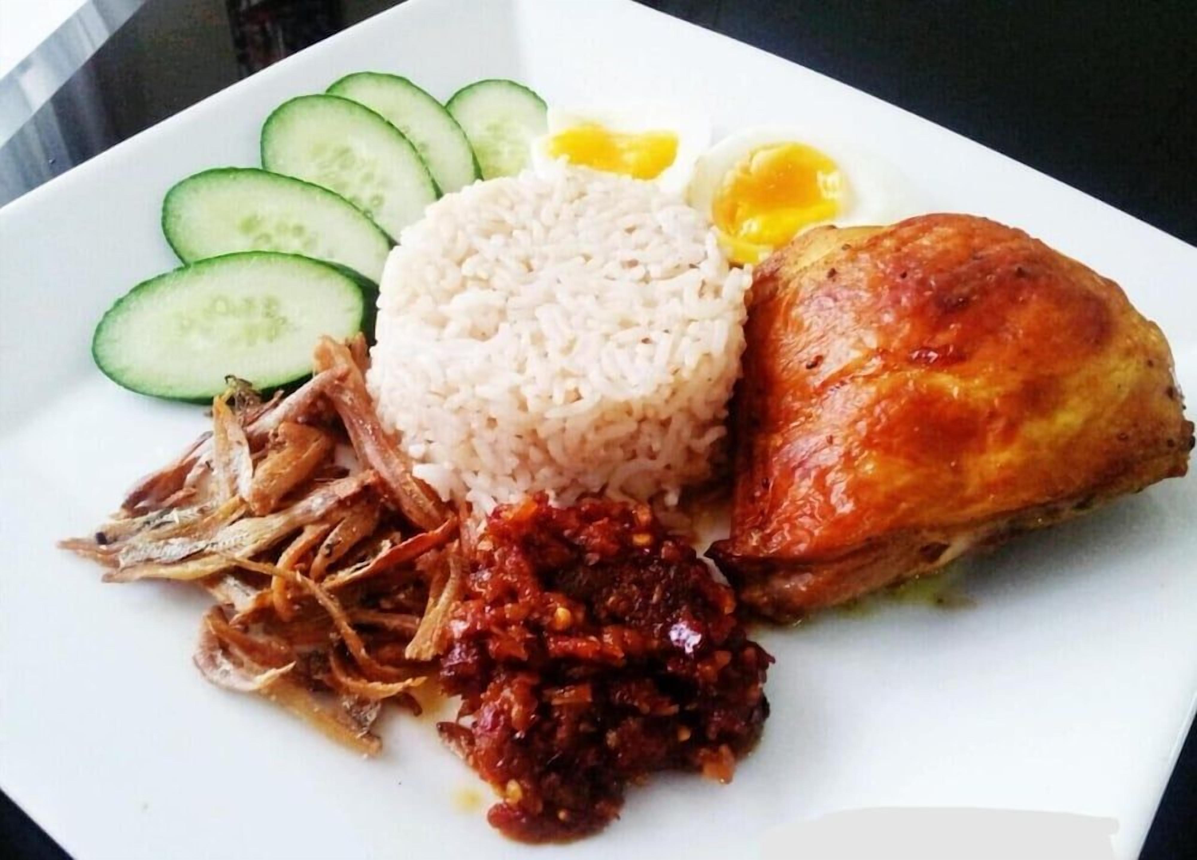 A plate of food with rice, a fried egg, cucumber slices, and a piece of meat.