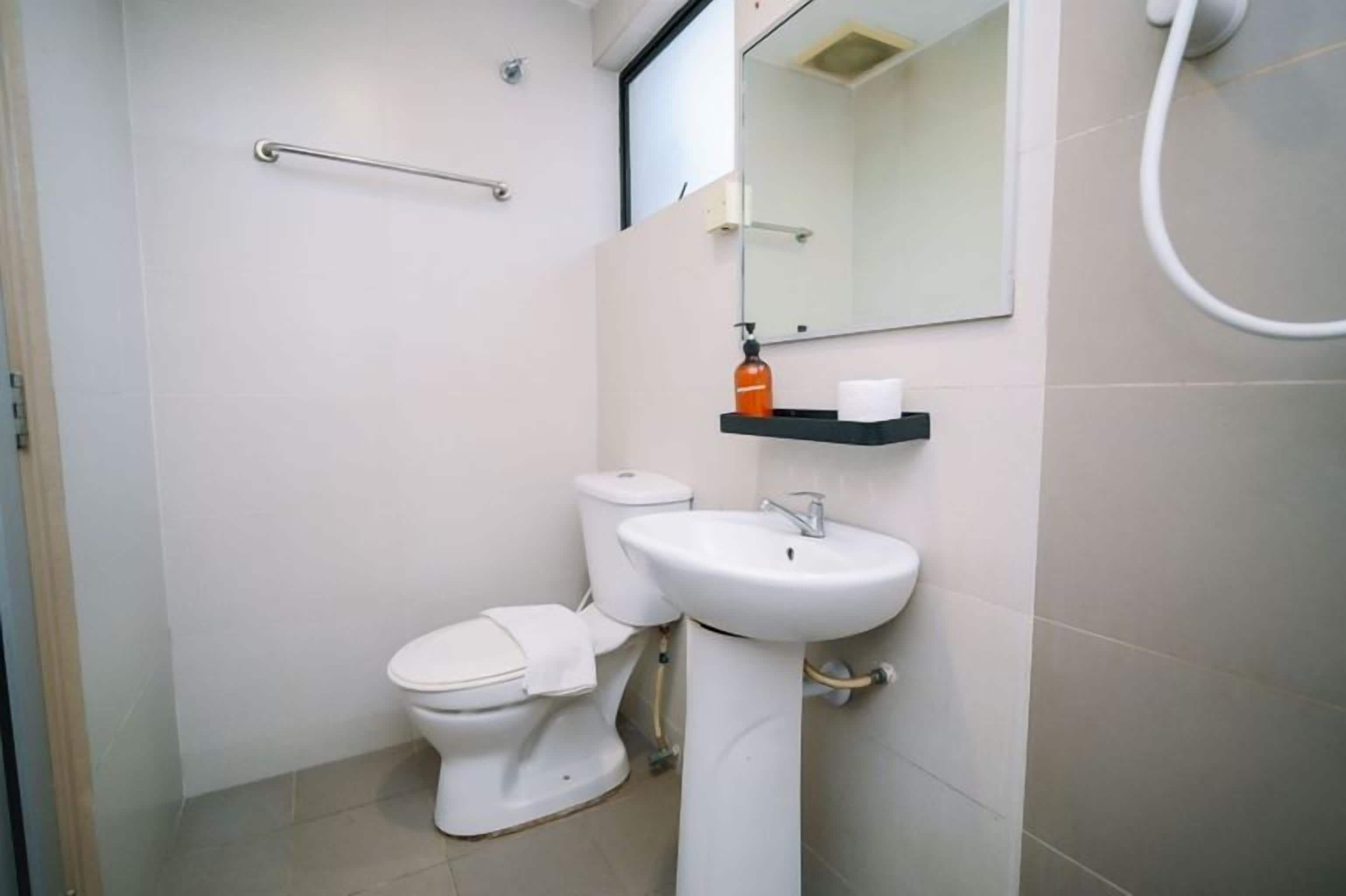 A bathroom with a toilet, sink, and a mirror.