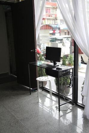 A room with a desk, computer, and chair, a door, and a view of the street outside. - Swing & Pillows @ KL Pekeliling (Kuala Lumpur)