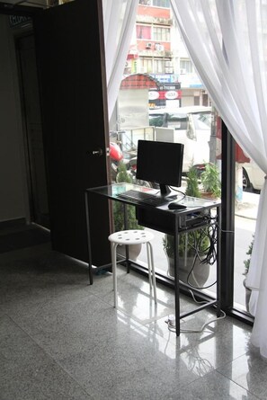 A room with a desk, computer, and chair, a door, and a view of the street outside. - Swing & Pillows @ KL Pekeliling (Kuala Lumpur)