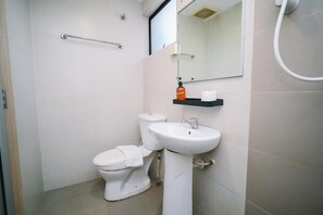 A bathroom with a toilet, sink, mirror, and handrail. - Swing & Pillows @ KL Pekeliling (Kuala Lumpur)