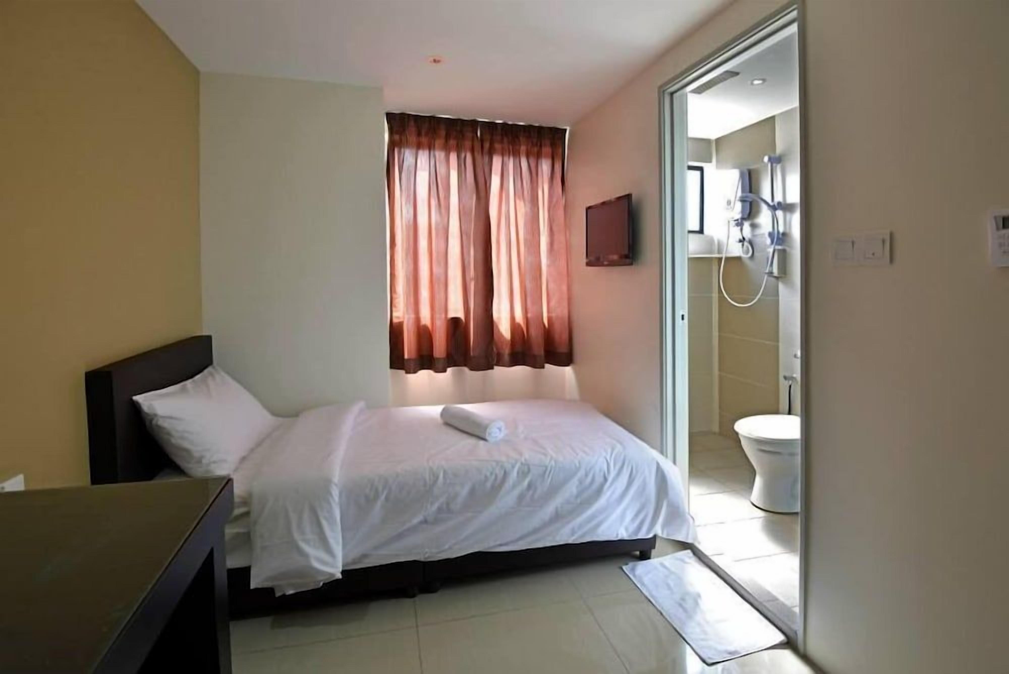 A hotel room with a bed, a desk, a television, a bathroom with a toilet and shower.