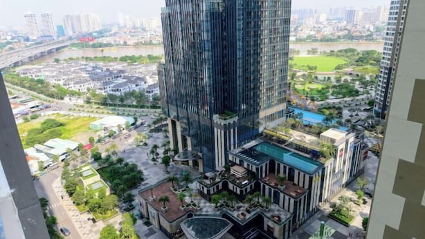 Um edifício alto com fachada de vidro moderna, rodeado por área ajardinada com piscina e área de estar externa.