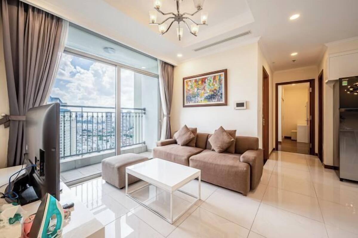 A modern living room with a large window, a sofa, a coffee table, and a TV.