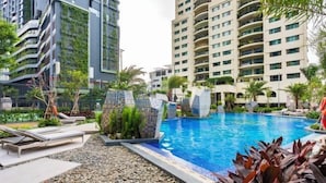 Um hotel moderno com piscina, rodeado por vegetação e palmeiras.