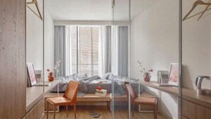 Un dormitorio moderno con cama, mesitas de noche, un escritorio y una silla.