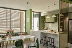 A modern kitchen with a white countertop, green accents, and bar stools. - Express by M Village Global City, a brand of Modern Village Lifestyle (Ho Chi Minh City)