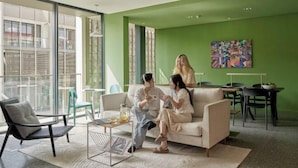 Una sala de estar moderna con un ventanal grande, una pared de acento verde y un comedor con mesa y sillas.