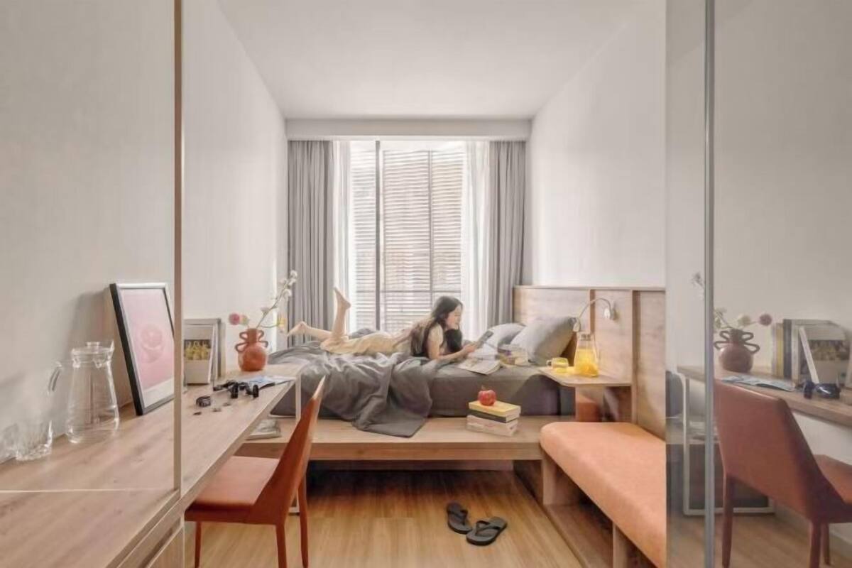 Ein kleines Schlafzimmer mit Bett, Nachttisch und Schreibtisch.