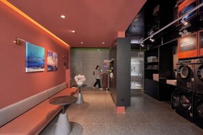 A hotel lobby with a reception desk, seating area, and laundry facilities.