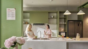 Una cocina moderna con una isla central, paredes verdes e iluminación colgante.