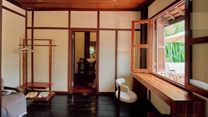 Ein traditioneller japanischer Raum mit Tatami-Bodenbelag, Holzboden und einer Schiebetür, mit Blick auf viel Grün.