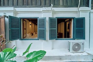 Un bâtiment doté de trois fenêtres ouvertes, d’une façade blanche et d’un appareil de climatisation.