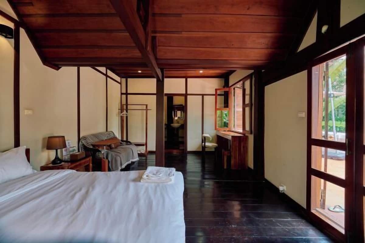 A hotel room with a bed, a desk, a chair, and a window.