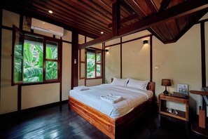 Une chambre à coucher avec un lit en bois, une table de chevet et une fenêtre donnant sur un paysage verdoyant.