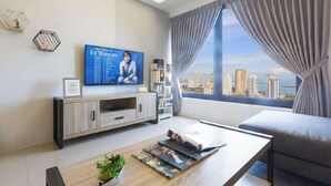 A modern living room with a flat-screen TV, a coffee table with magazines, a sofa, and a large window with curtains. - Mona Homes #6 Macalister 218, Georgetown Penang (George Town)