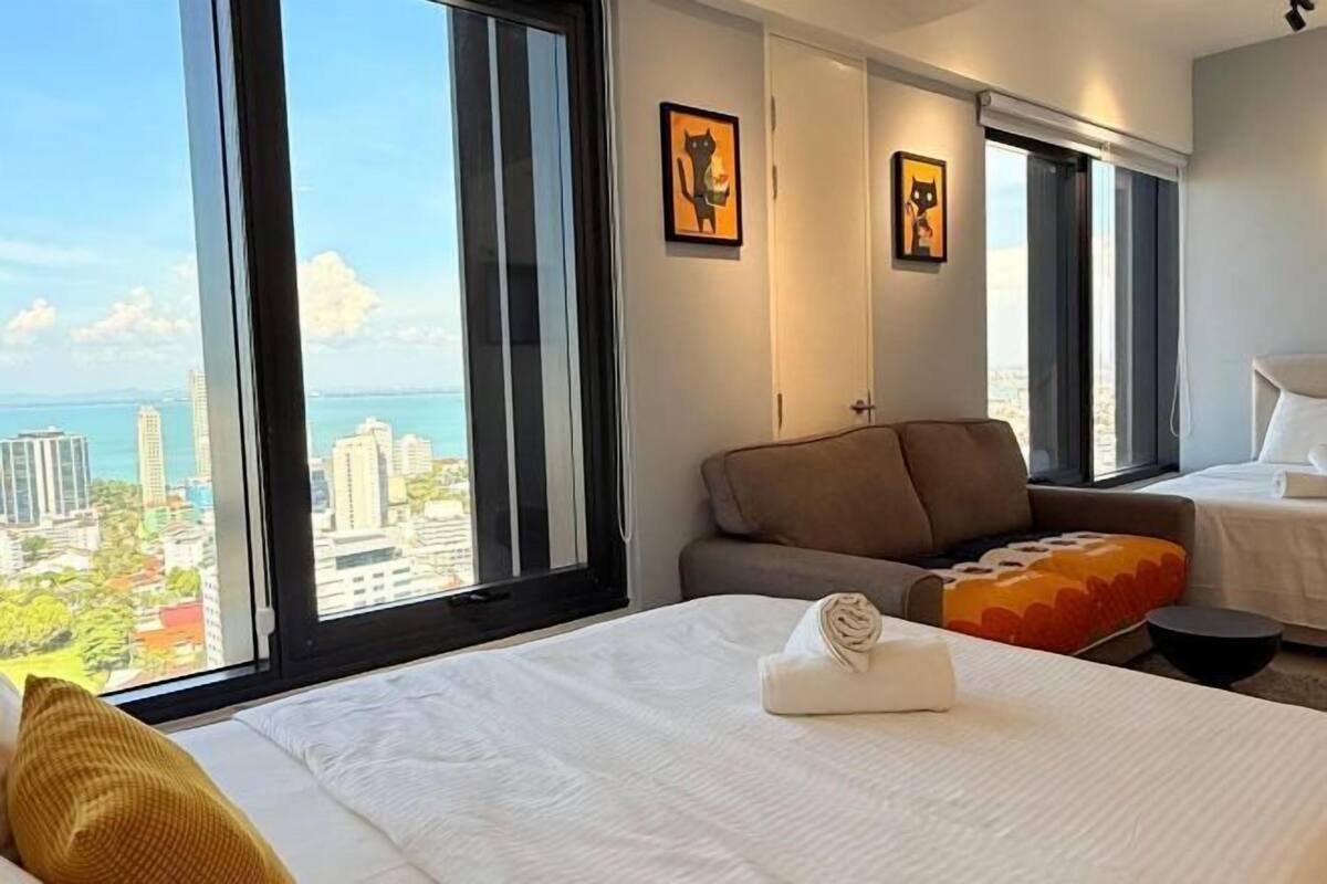 Une chambre d’hôtel avec un lit, un canapé, une fenêtre donnant sur la ville et deux tableaux encadrés accrochés au mur.