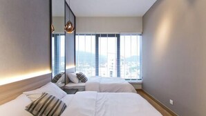 A modern hotel room with two beds, a large mirror, and a city view through the window. - Mona Homes #6 Macalister 218, Georgetown Penang (George Town)