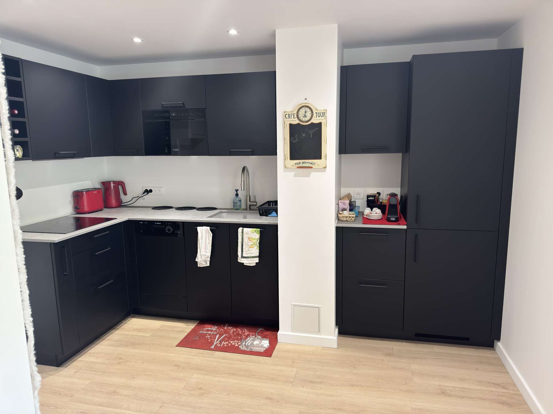 Een koelkast, een vaatwasser, kookgerei, borden en bestek