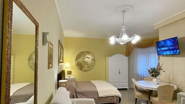 Une chambre d’hôtel avec deux lits, une table à manger, un téléviseur et un globe décoratif mural.