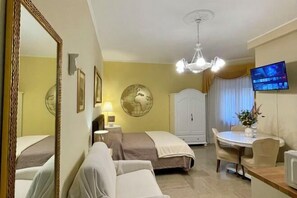 Ein Hotelzimmer mit zwei Betten, einem Esstisch, einem Fernseher und einer Wanddekoration mit Globus.