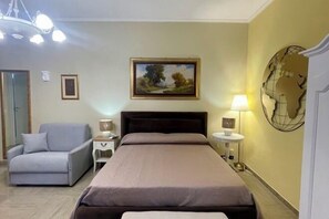 A bedroom with a bed, a chair, a nightstand, a lamp, and a painting on the wall. - Barbi's Home- Colli Albani Roma (Rome)