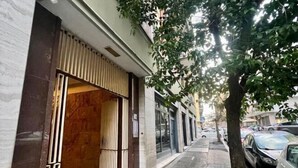 Une vue de rue avec un bâtiment doté d’une grande entrée en verre et d’un trottoir bordé d’arbres.