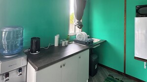 Een keuken met een waterdispenser, een magnetron en een spoelbak.