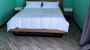 Een kamer met een bed, twee nachtkastjes, een wandairconditioner en een visgraatvloer.
