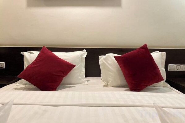 A bed with white linens and two red pillows.