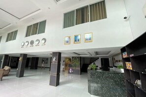 A hotel lobby with a reception desk, seating area, and a large plant. - Apple Hotel Two (Phnom Penh)