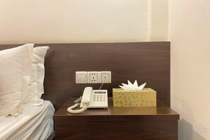 Une chambre d’hôtel équipée d’un lit, d’un téléphone sur la table de chevet, d’une prise électrique et d’une boîte de mouchoirs.