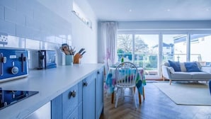 A modern kitchen with a dining area, large windows, and a view of the outside. - Footsteps - 2 Bedroom Apartment - Saundersfoot (Saundersfoot)