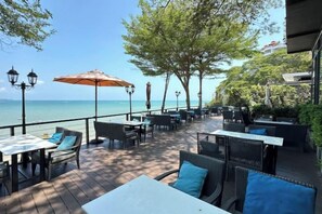 An outdoor patio with tables and chairs, overlooking a body of water. - Majestic Residence Pool 51, Pratumnak, Pattaya (Pattaya)
