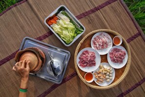 Ein Picknick mit einem Topf, einer Platte mit Fleisch, Gemüse und Dipsaucen.