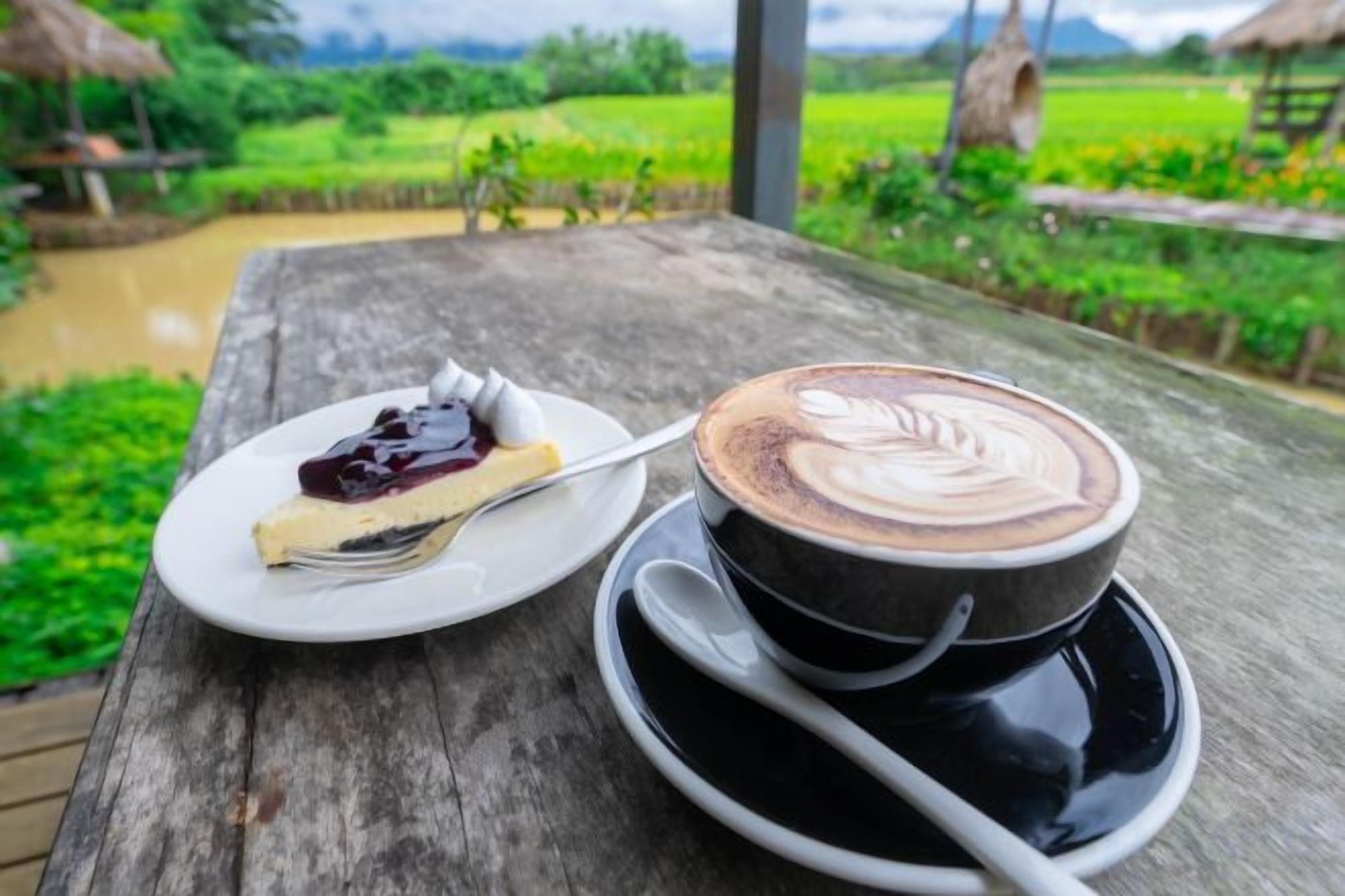 A wooden table with a plate of dessert and a cup of coffee with latte art.