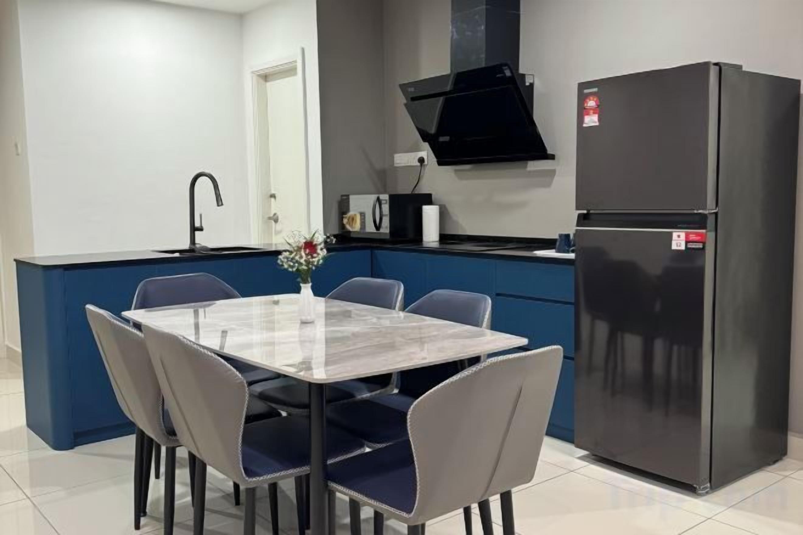 A compact kitchen with a dining area, a black refrigerator, and a blue accent wall.