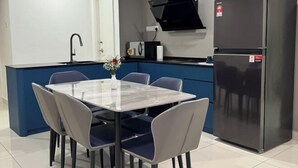 A compact kitchen with a dining table, chairs, a refrigerator, and a microwave. - Southkey Mosaic @ sweethome (Johor Bahru)